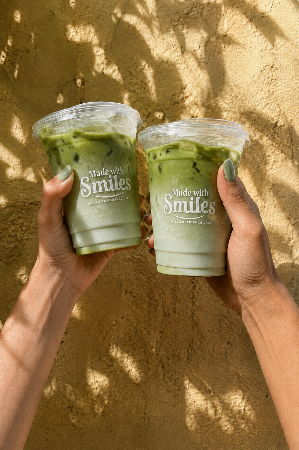 Two guests holding Made with Smiles iced matcha lattes in natural sunlight